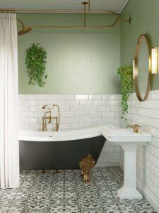 A green bathroom wall with half tiled white subway tiles