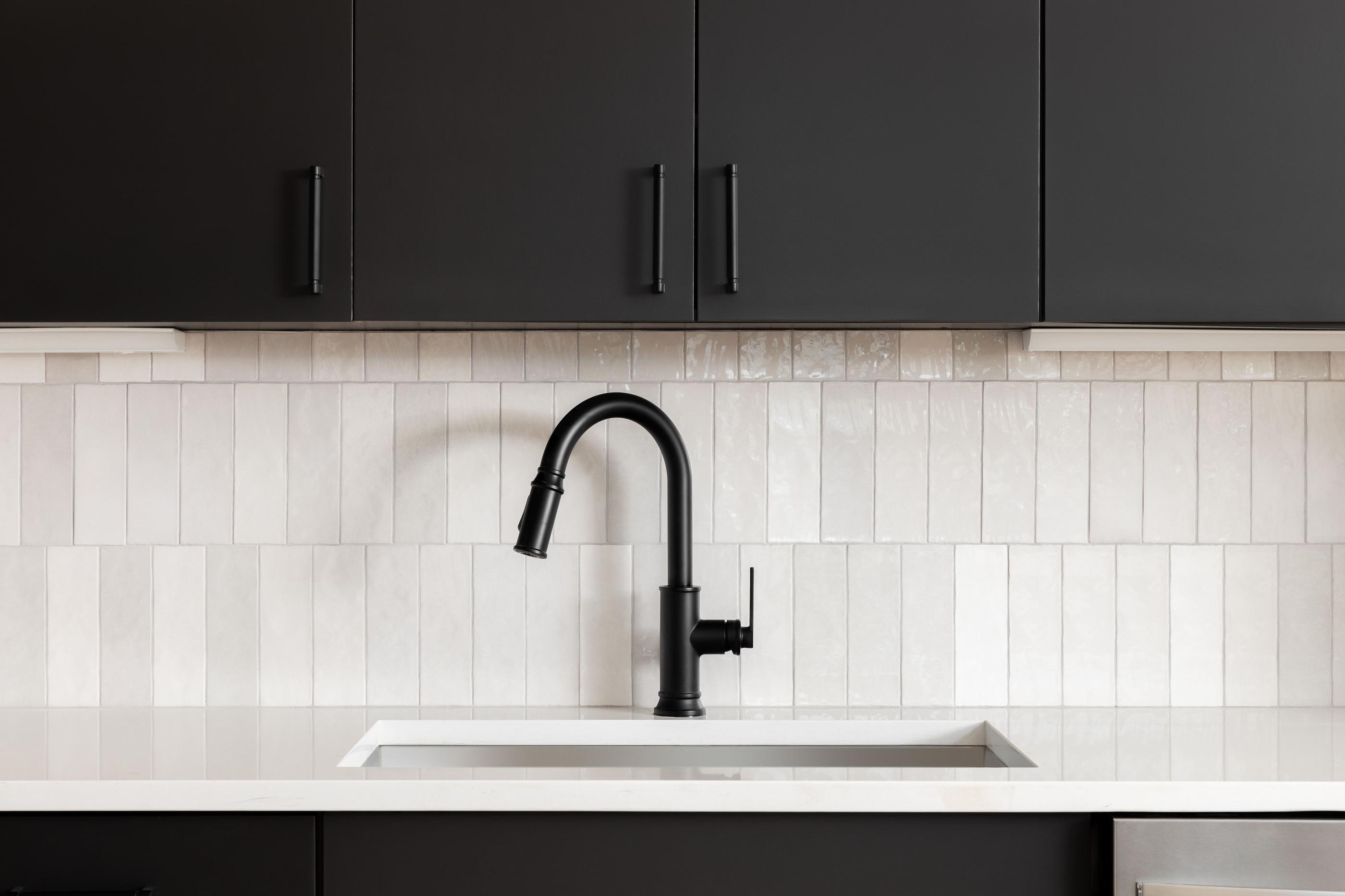 Vertically aligned zellige tile contrasting with dark kitchen fixtures.