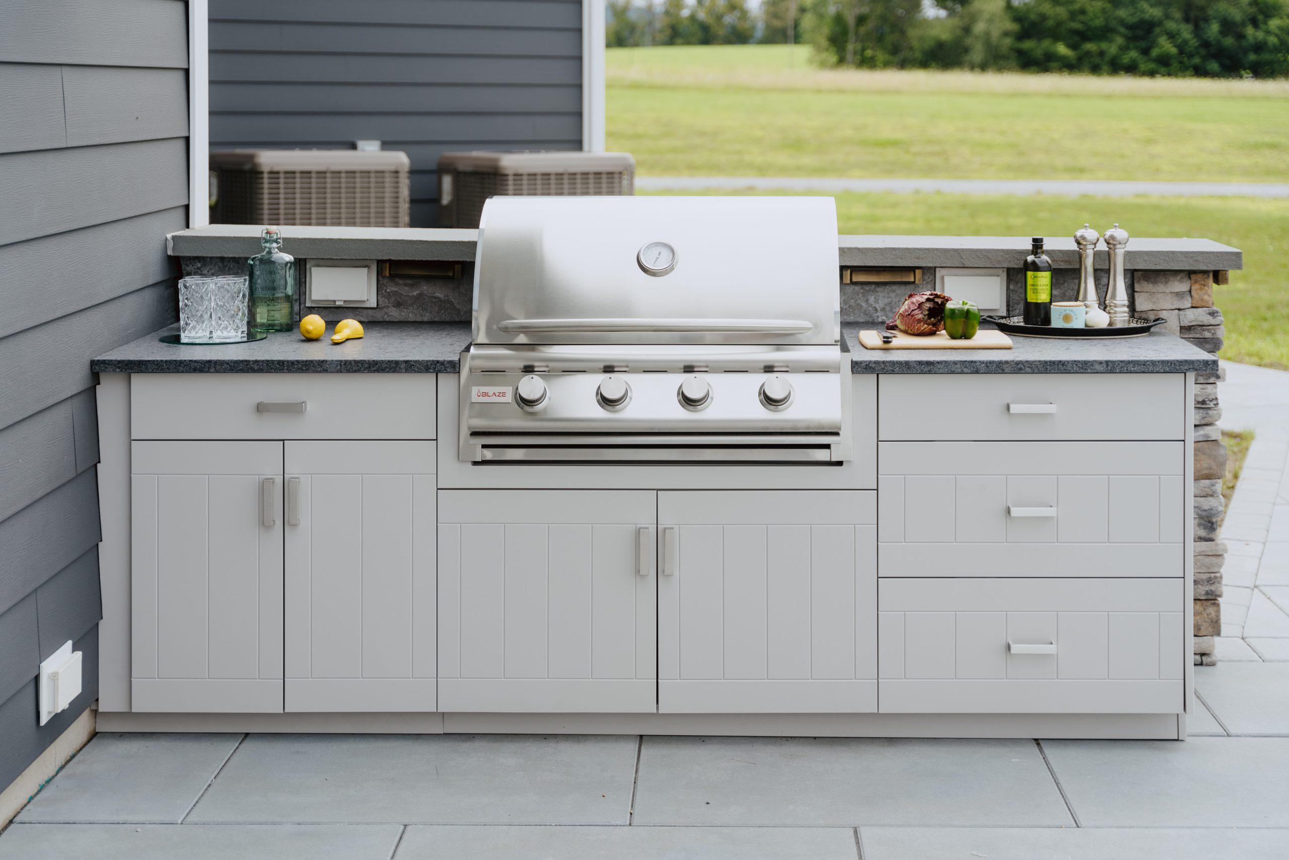 Light grey outdoor kitchen cabinets with a built in grill.