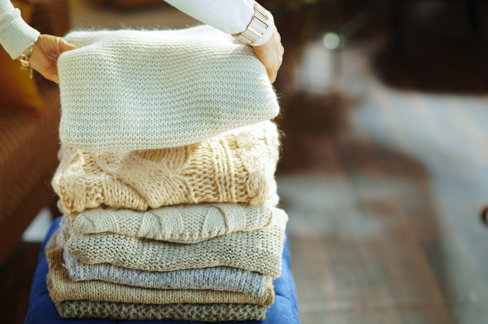 Variety of thick, winter sweaters being sorted for smart storage.