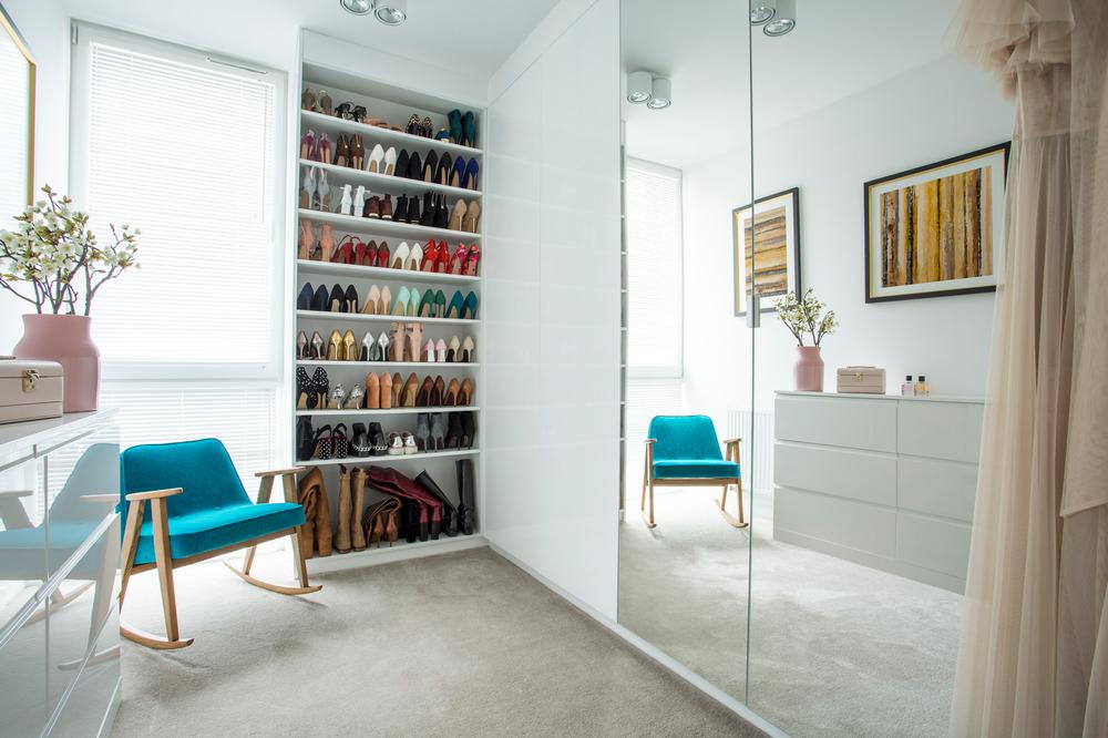 Walk in closet with blue chair and shoe display
