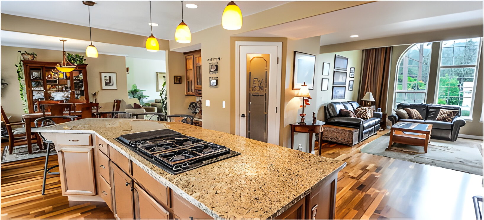 Open concept kitchen with a large granite-top island that has an embedded gas cooktop. The kitchen looks out into the home's living and dining room.