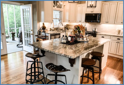 A traditional kitchen customized with a large granite island and stool seating, whitewashed kitchen cabinets, and a subway tile backsplash