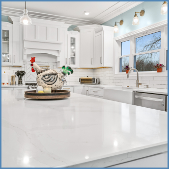 View across the top of an expansive white kitchen island in an l-shaped kitchen with white cabinets and white subway tiling