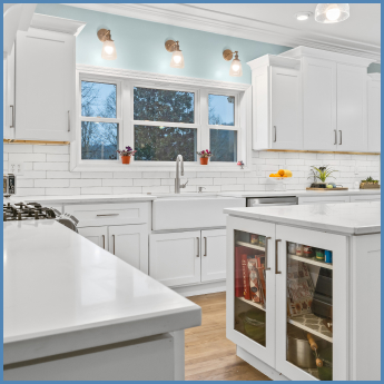 L-shaped kitchen remodeled with white cabinets and countertops, white subway tiling, and an island with glass door cabinet storage