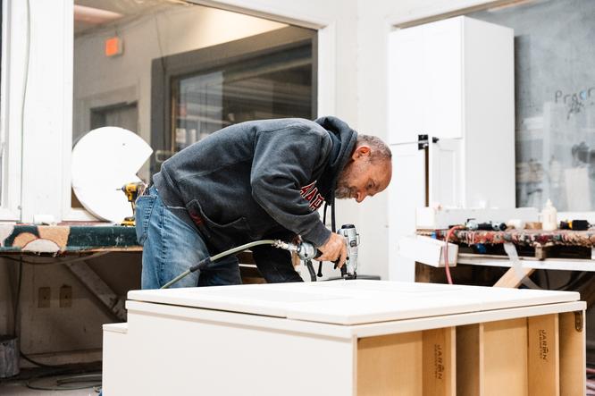 A Designery expert reviews tiling and hardware with a customer in a staged kitchen in The Designery showroom