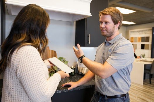 A Designery expert consults with a customer who is holding a white subway tile for backsplashes