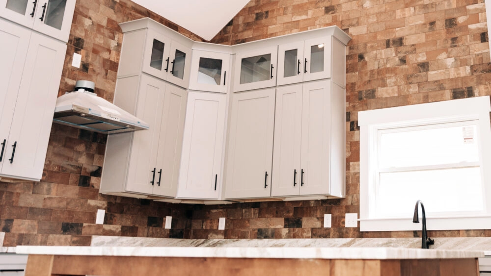 Upper kitchen cabinets with a rows white shaker style doors and a set of smaller glass accent doors at the top