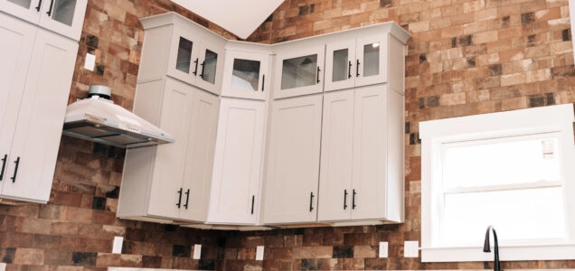 Upper kitchen cabinets with a rows white shaker style doors and a set of smaller glass accent doors at the top