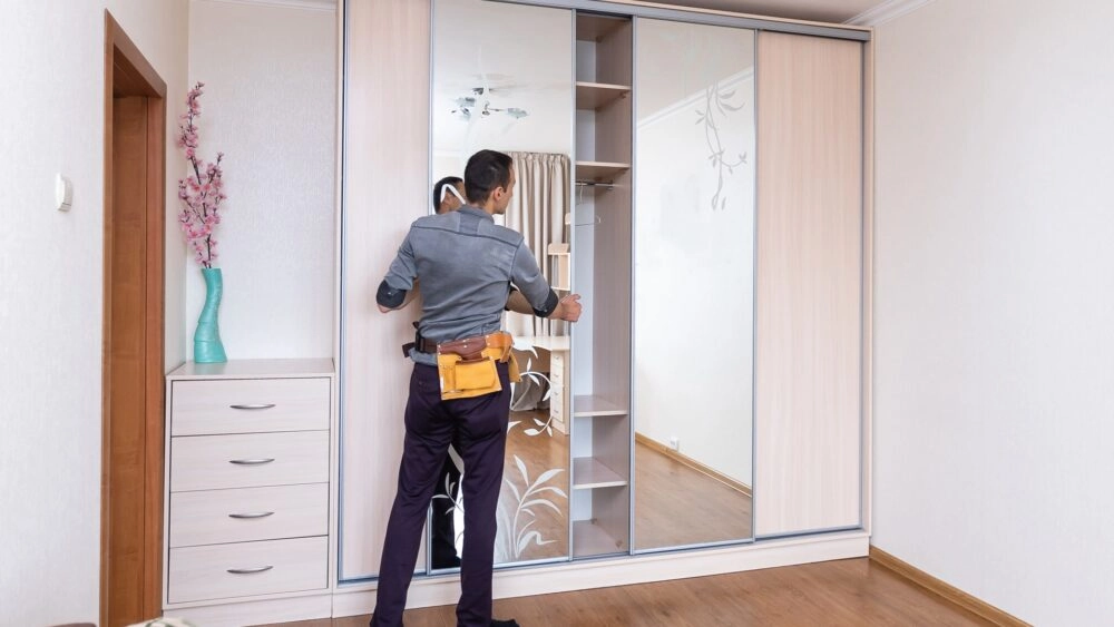 A closet installation expert tests the sliding mirror doors on a new closet remodeling project