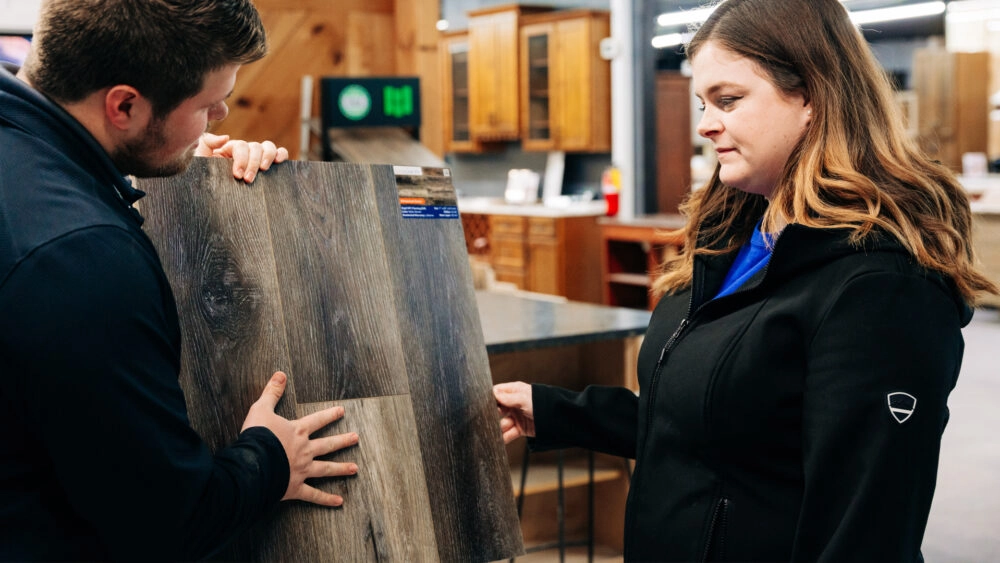 A Designery expert shows a customer a sample of luxury vinyl flooring in The Designery showroom