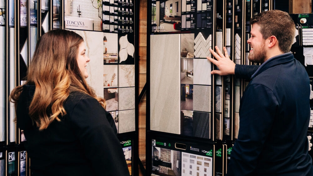 A Designery expert flips through sample countertop and backsplash materials with a customer in The Designery showroom