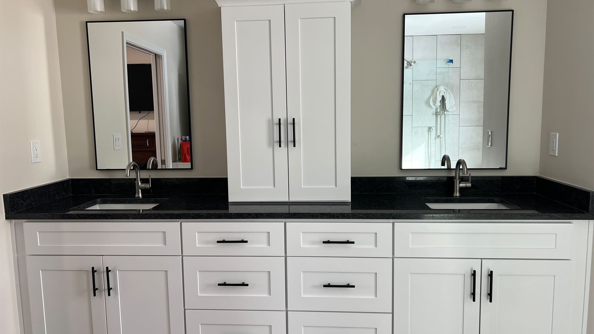 Contemporary black and white bathroom double sink vanity with white shaker lower cabinets and a black stone countertop