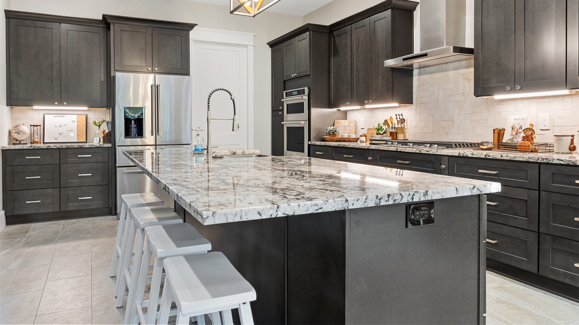 Contemporary l-shaped kitchen with charcoal gray shaker cabinets, white marbled stone countertops, and a spacious kitchen island with a built-in sink