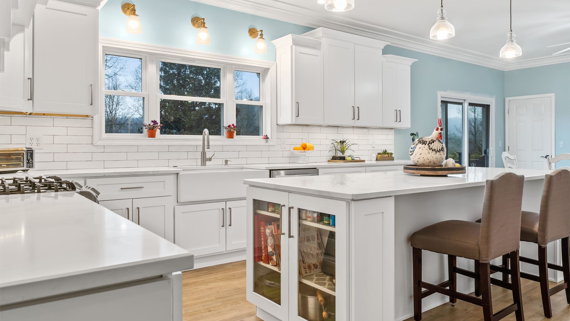 An airy white kitchen remodeled with all white shaker cabinets, white subway tiling, and a white kitchen island with stool seating