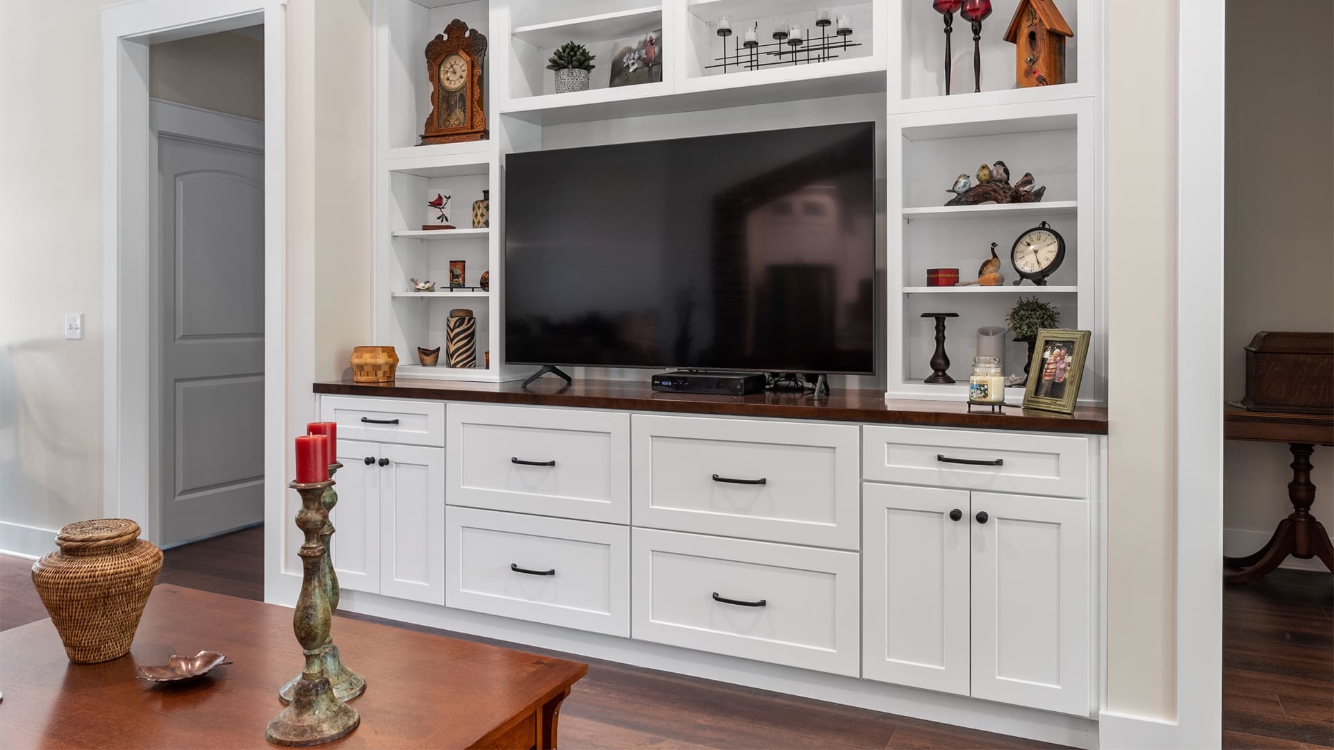 Modern entertainment center with white built-in shaker cabinets and open shelving around a flat screen tv