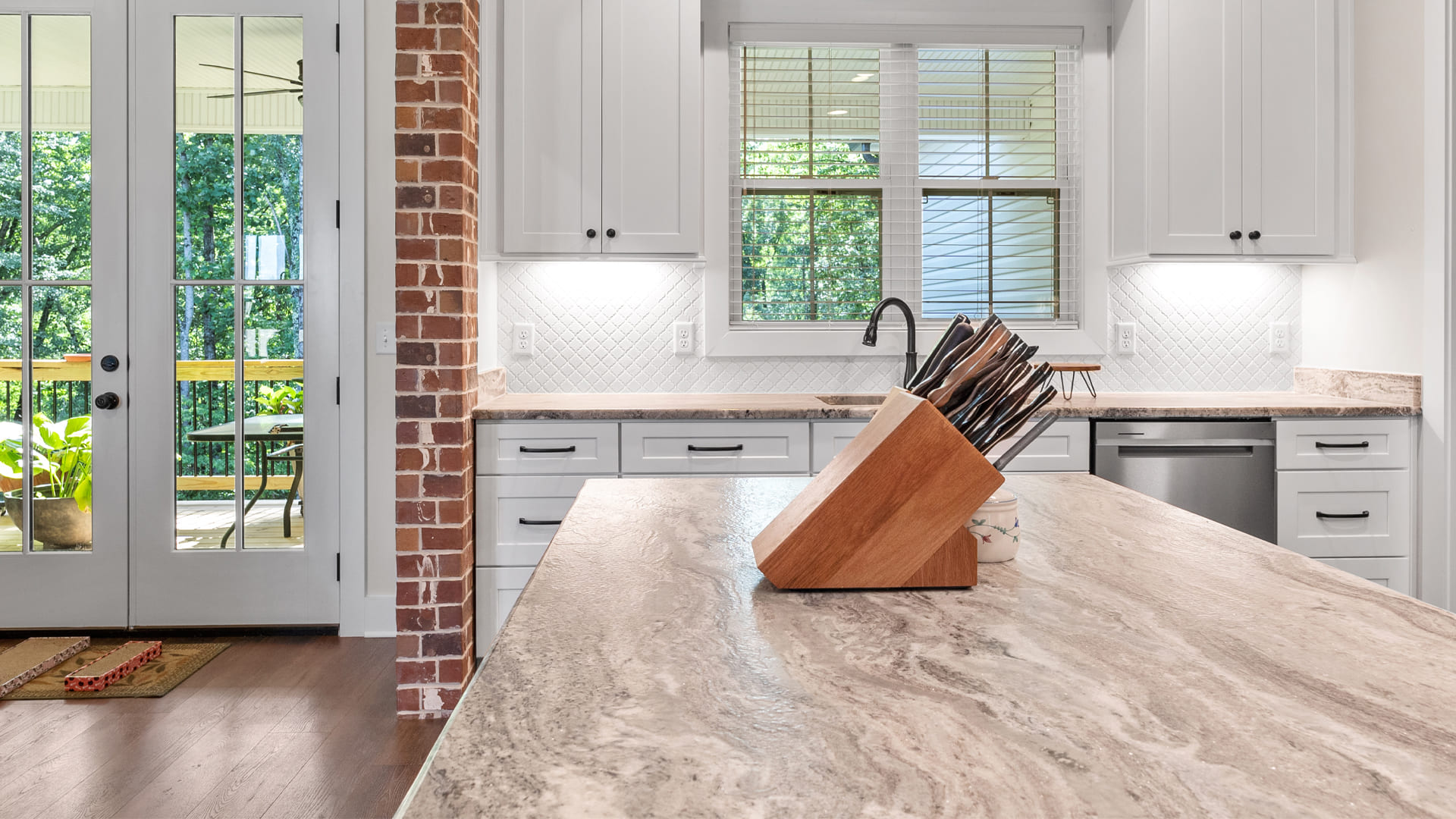 Inviting remodeled kitchen with white shaker cabinets and a large kitchen island with a marbled taupe countertop