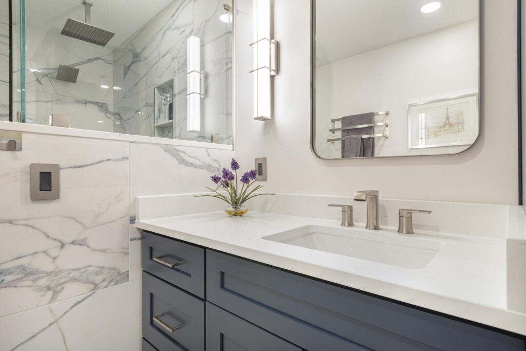 Half-tiled wall compliments the statement shower with grey veining and a contrasting dark blue vanity.