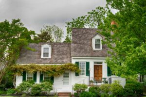 Historic home features a natural wooden door and beautiful, lush overgrowth that adds to the charm of the home.