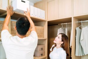 A couple works together to organize storage bins in a custom closet.