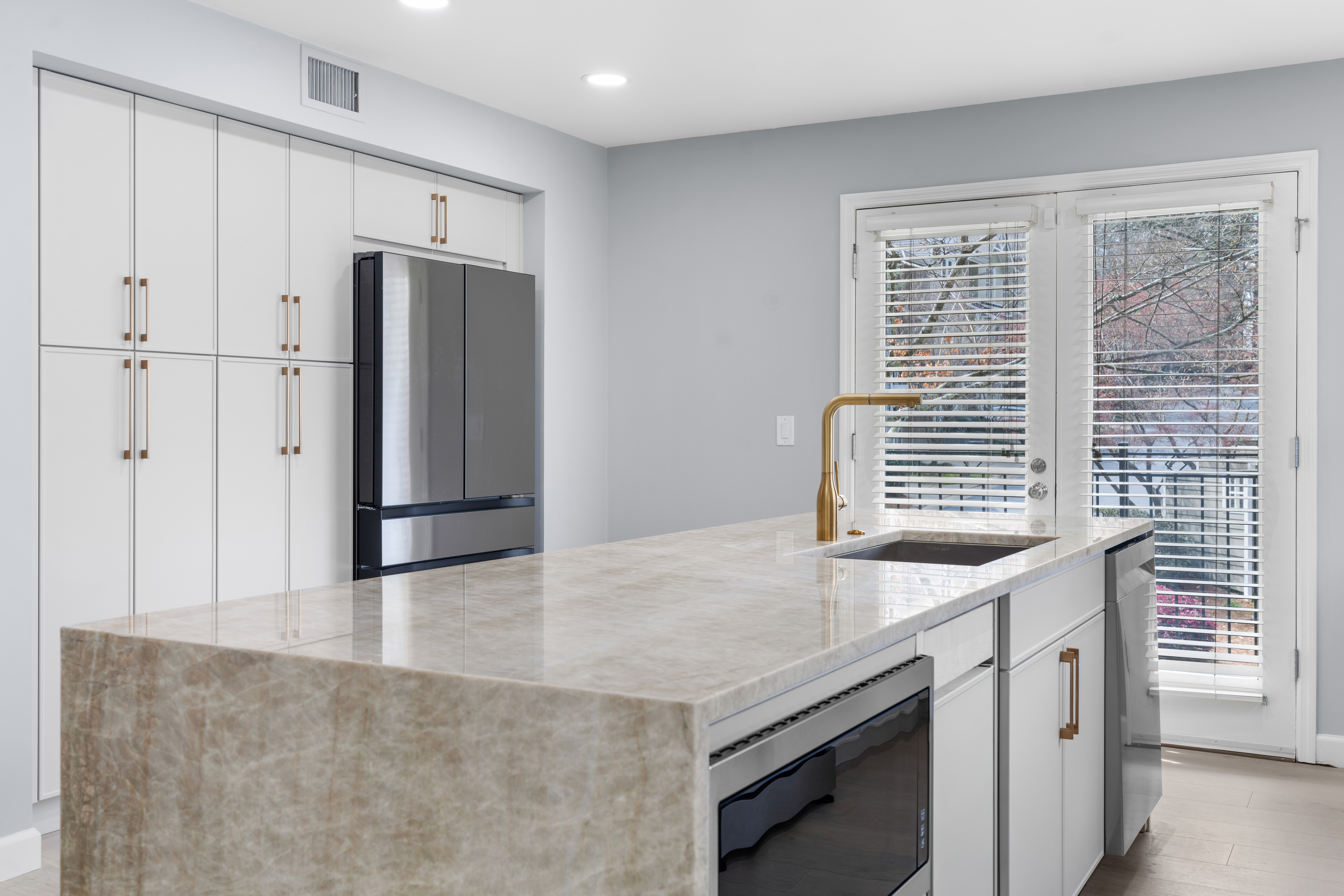 Open concept kitchen with a large granite-top island that has an embedded gas cooktop. The kitchen looks out into the home's living and dining room.